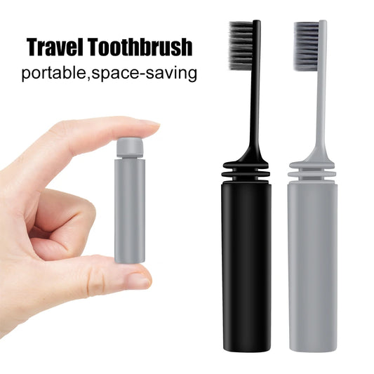 Travel toothbrush with black and gray bristles, held by a hand, on a white background.