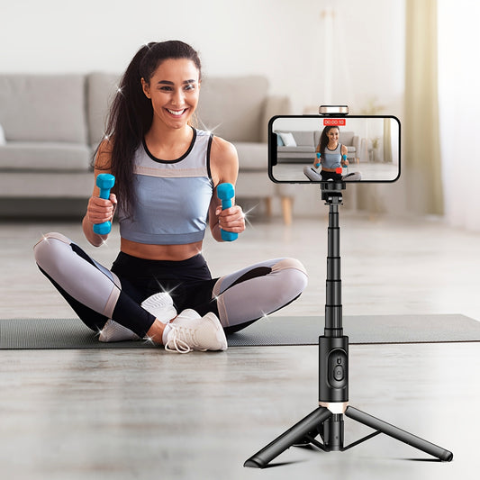 Woman exercising with dumbbells, using a smartphone on a tripod to record or take a photo.