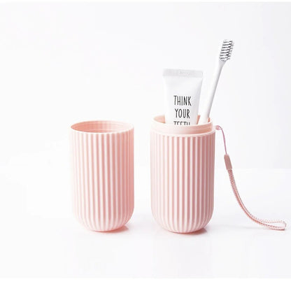 Two pink textured cups with a tube of toothpaste and a toothbrush on a white background