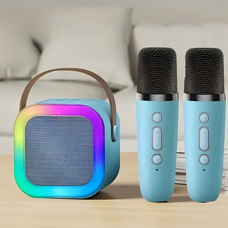 Portable speaker with rainbow gradient and two blue microphones on a wooden surface.