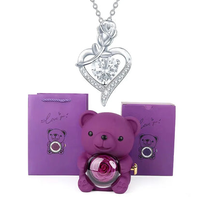 Purple teddy bear with rose and silver heart necklace on white background