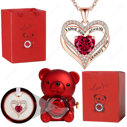 Heart-shaped necklace with red gem, red teddy bear, and red gift box on a white background