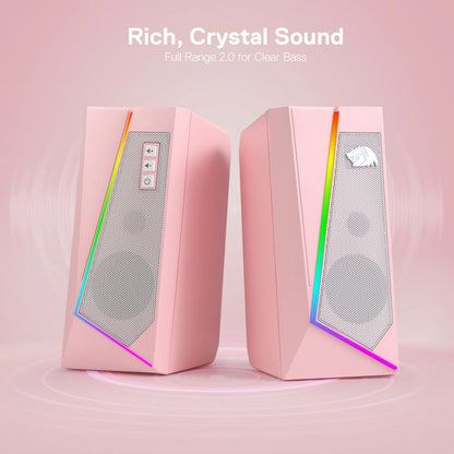 Pink computer speakers with RGB lighting on a pink background, featuring text about sound quality.