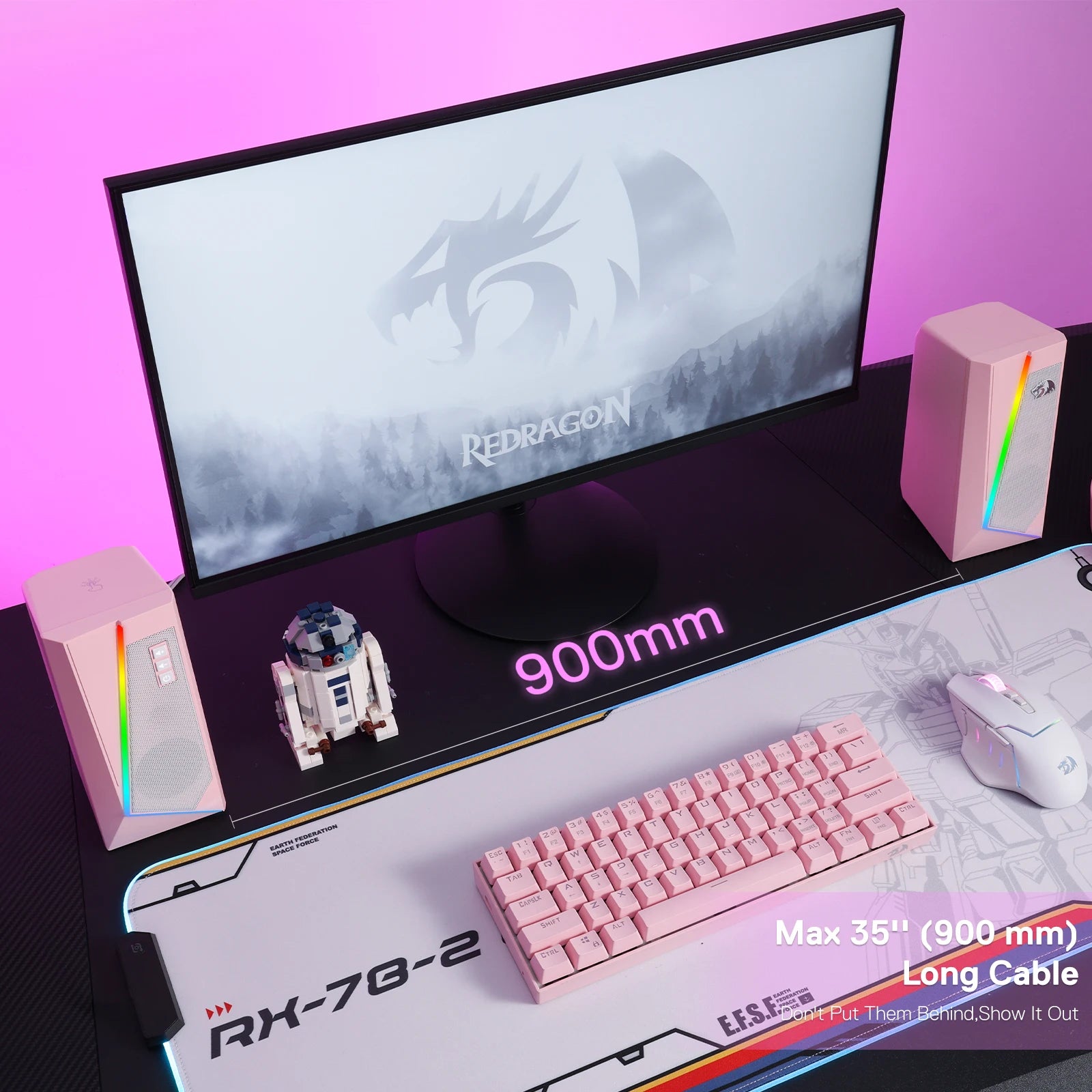 Gaming setup with monitor, keyboard, and speakers on a desk with a pink background