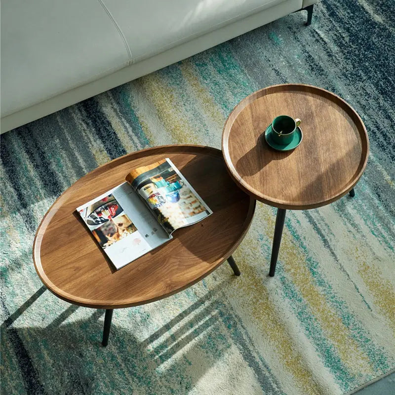 Two wooden side tables on a patterned rug with a magazine and a cup.