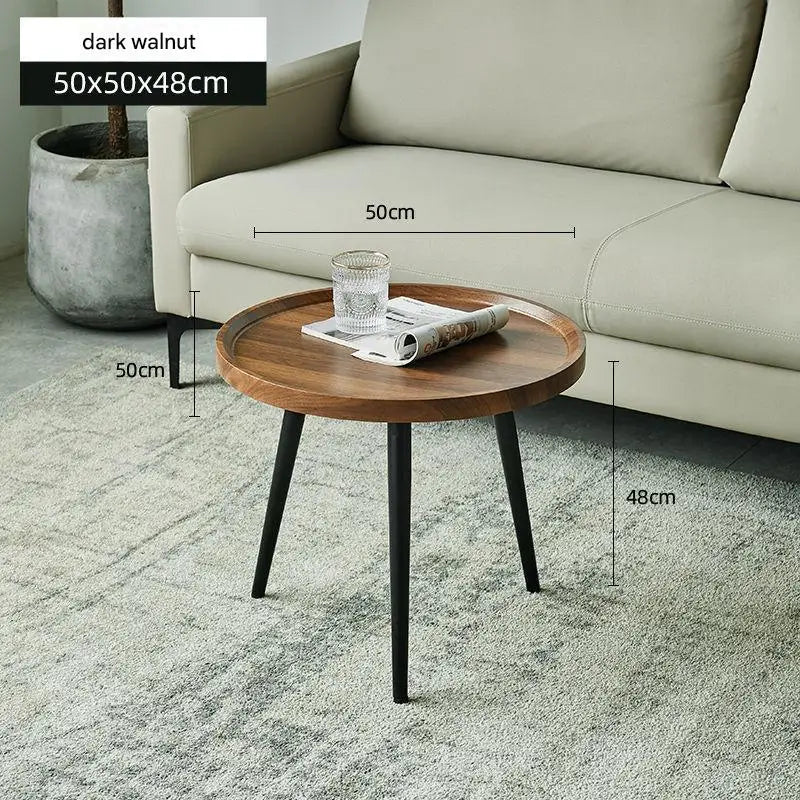 Round wooden side table with dimensions next to a beige sofa.