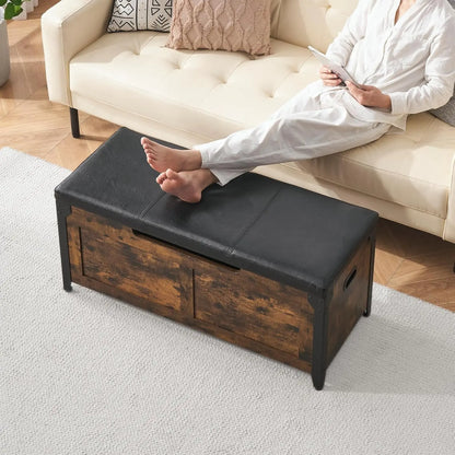 Person sitting on a beige sofa with a black and wooden storage bench in the foreground.