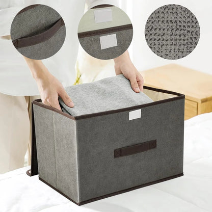 Gray storage box with brown accents being used to store a gray cushion on a bed.