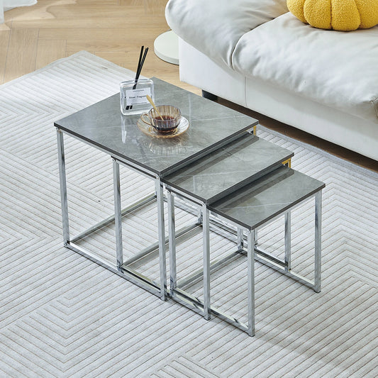 Set of three nesting tables with glass tops and metal frames in a living room setting.