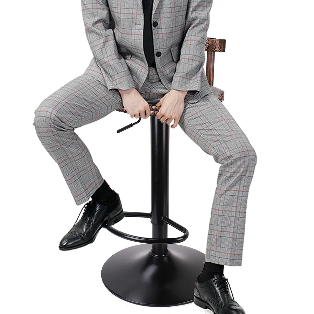 Person in a gray checkered suit sitting on a black adjustable stool against a white background
