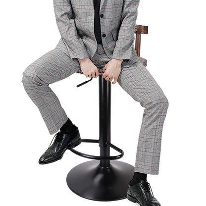 Person in a gray checkered suit sitting on a black adjustable stool against a white background