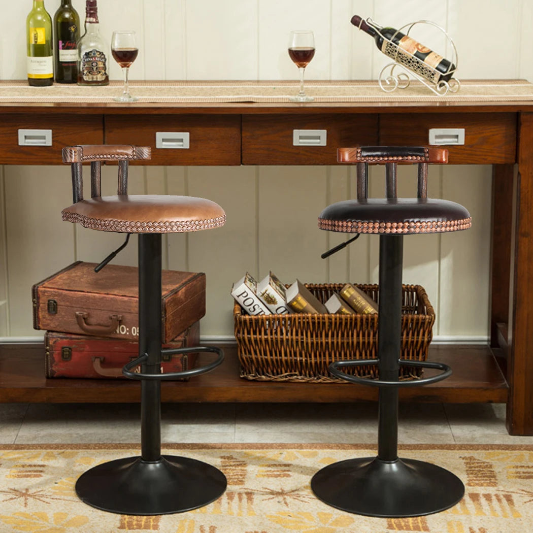 Two bar stools in front of a wooden bar with wine bottles and glasses.