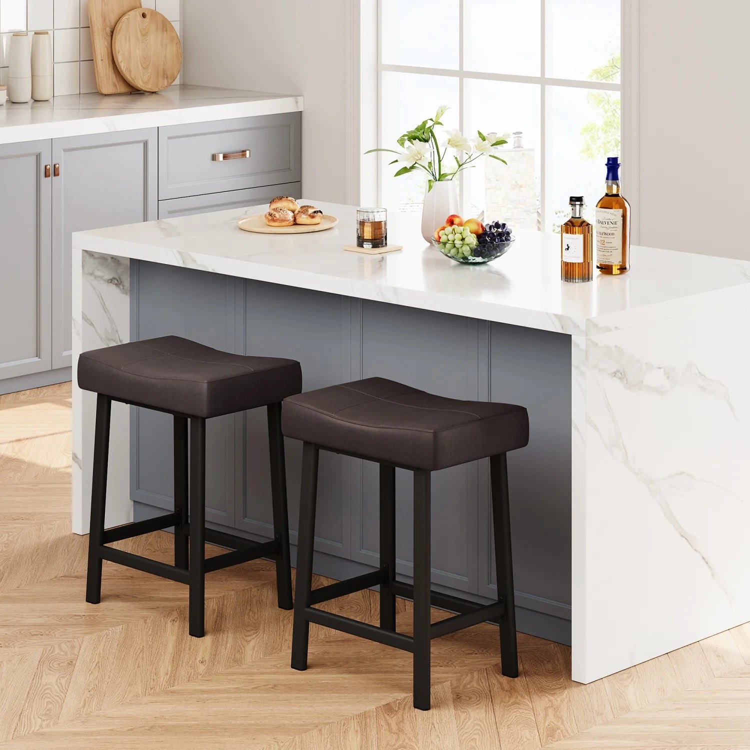 Two brown bar stools in front of a kitchen island with food and drinks.