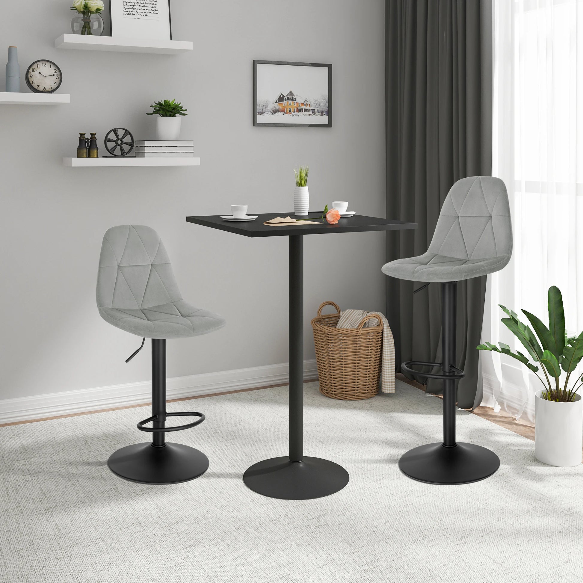 Two gray bar stools with black bases in a room with a small table and decor items.