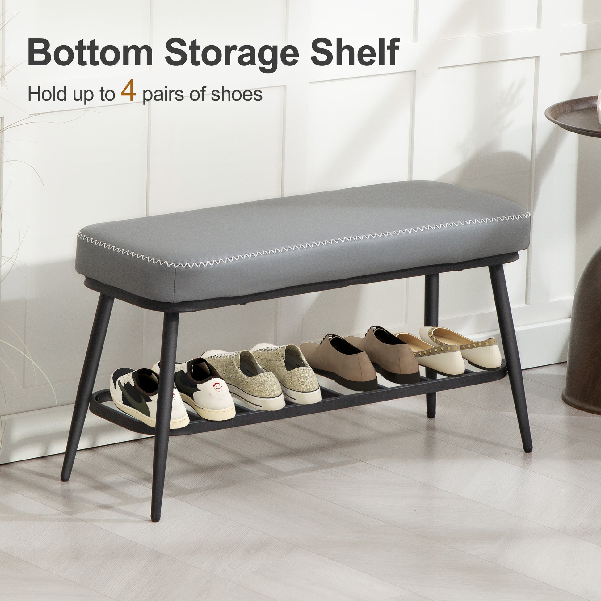 Gray shoe bench with storage shelf holding shoes against a white tiled wall.