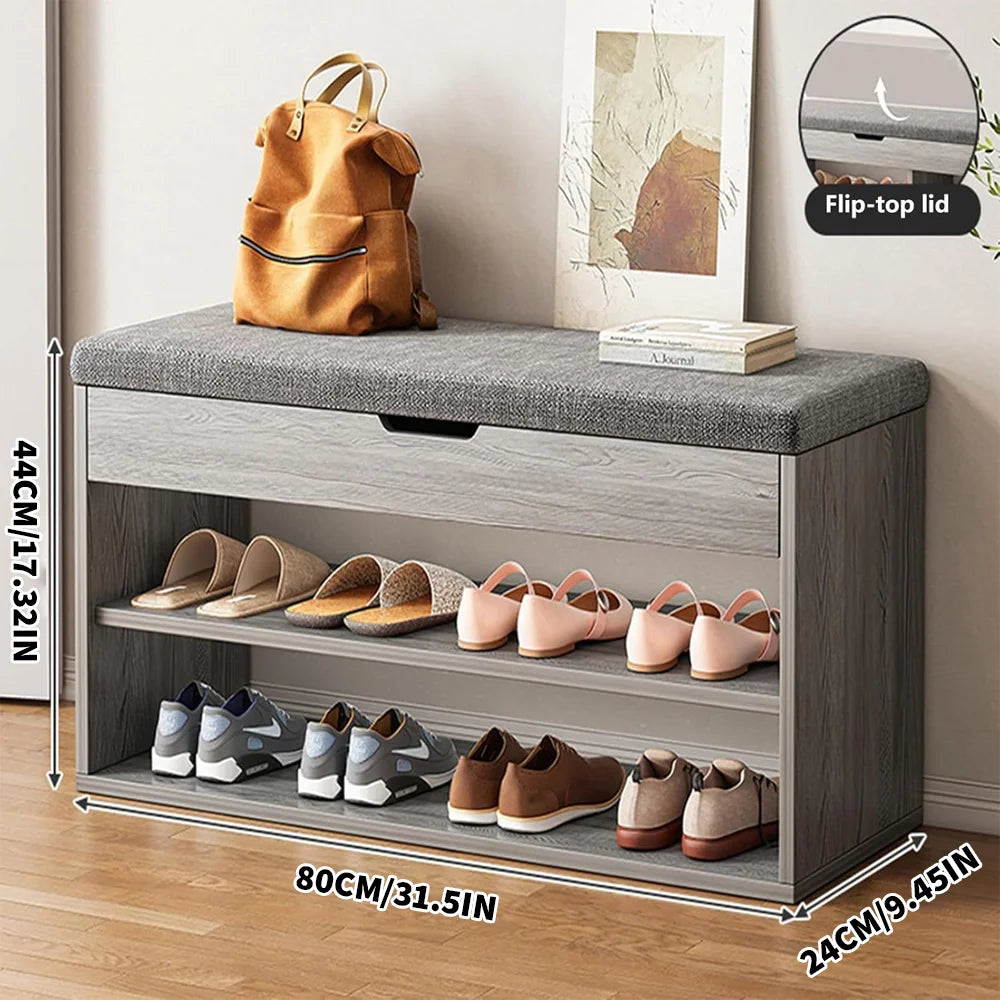 Gray shoe storage bench with flip-top lid, shoes, and a backpack on a wooden floor.