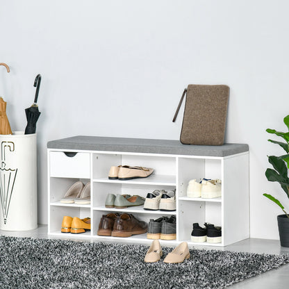 White shoe storage bench with gray top holding shoes and a bag, against a light gray wall.
