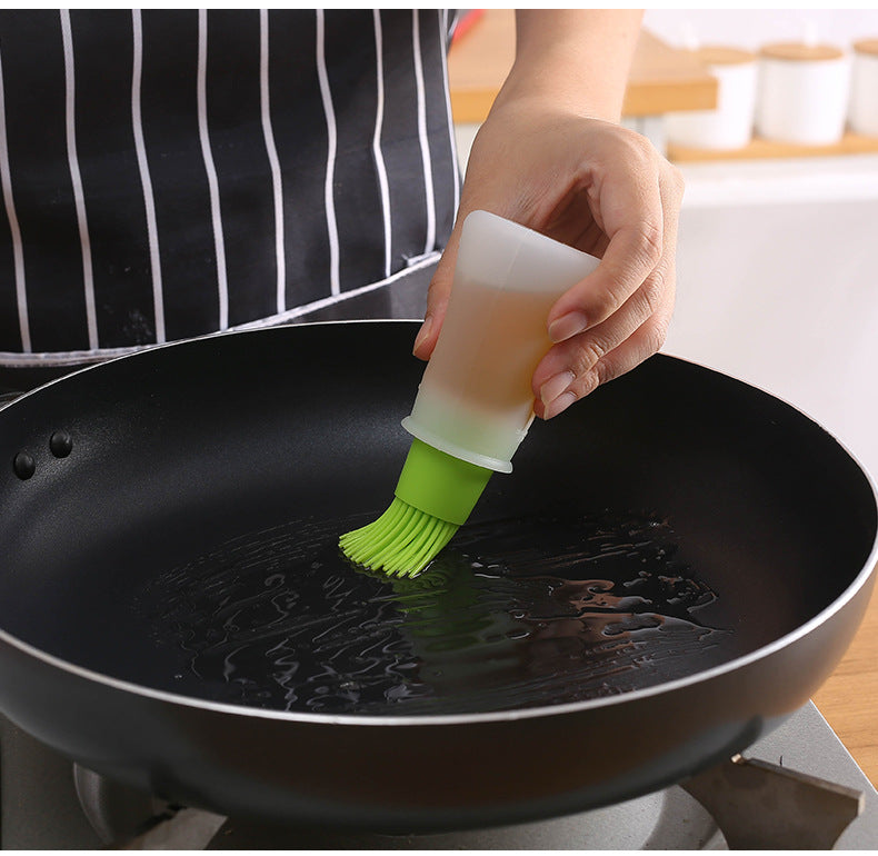 Person using a silicone brush to apply oil to a black frying pan