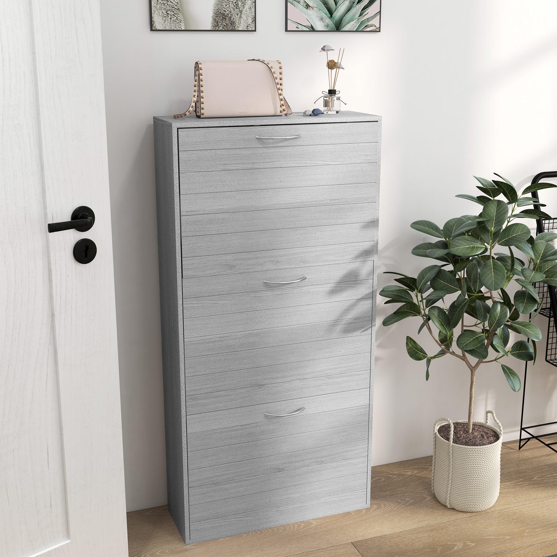 Tall gray shoe cabinet next to a plant in a room with a white door.