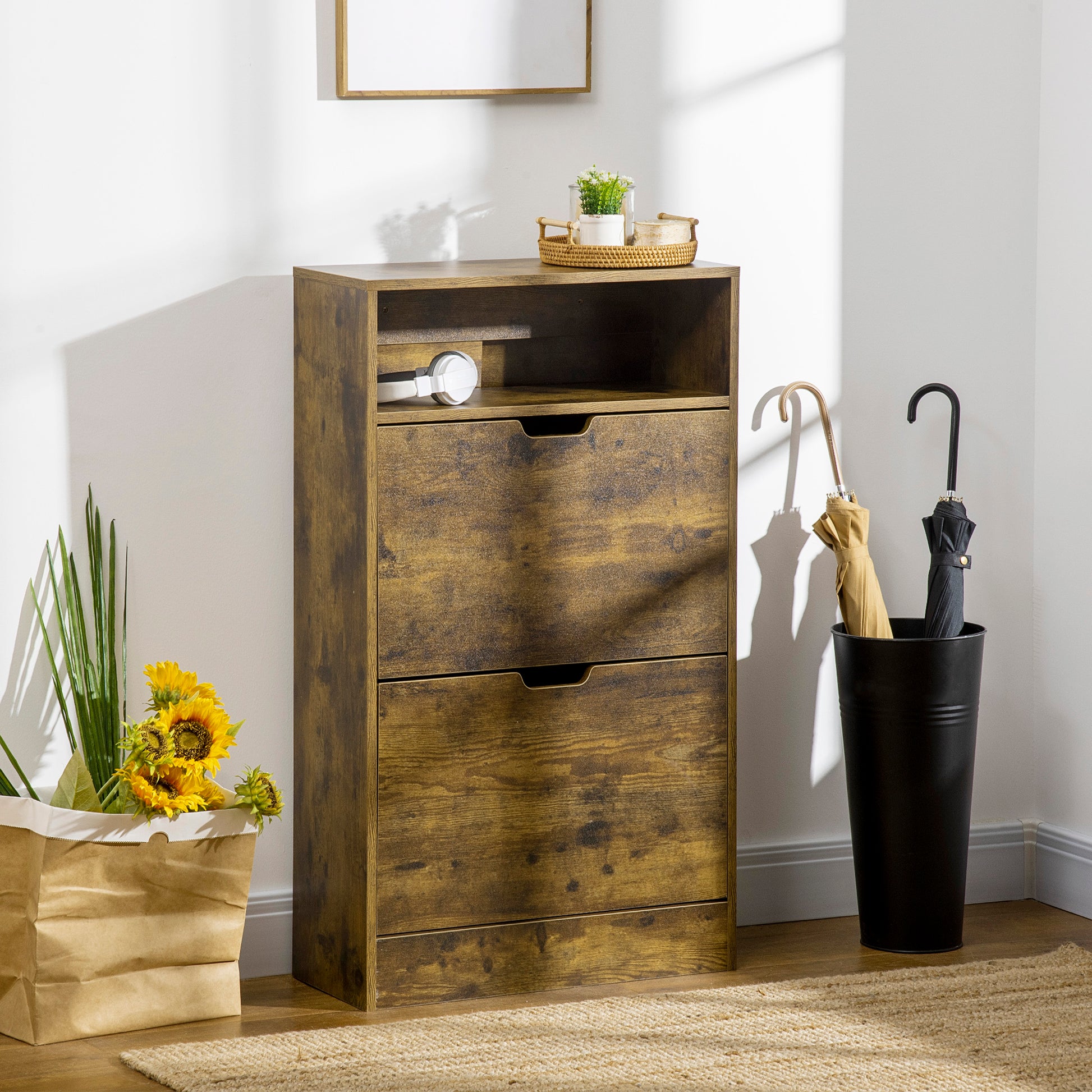 Wooden shoe cabinet with two drawers in a room setting with a black umbrella stand and plants.