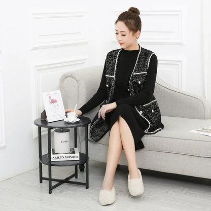 Woman in black and white outfit sitting on a gray sofa in a stylish room.