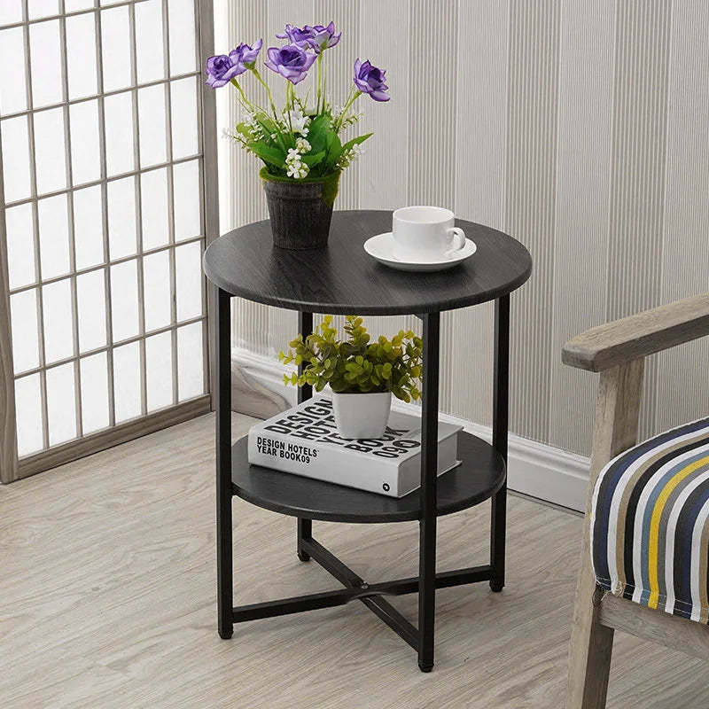 Black round side table with plants and a cup in a room with striped wallpaper.