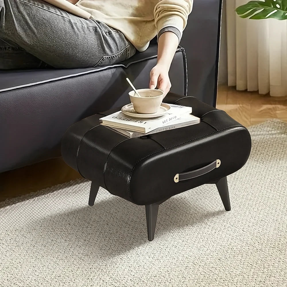 Black footstool with a person placing a cup on top, in a living room setting.