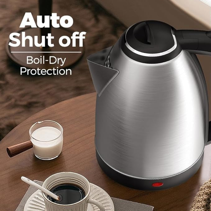 Silver electric kettle with black handle on a wooden table next to a glass of milk and a cup of coffee.