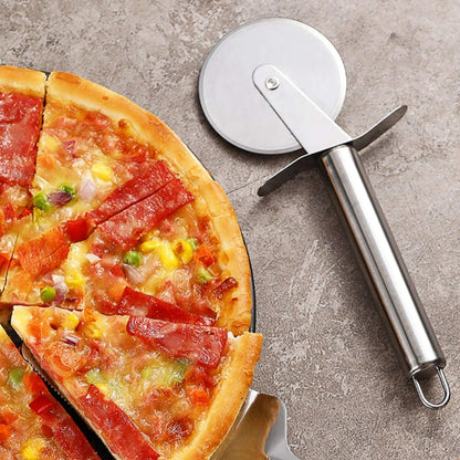 Pizza with various toppings and a pizza cutter on a concrete surface