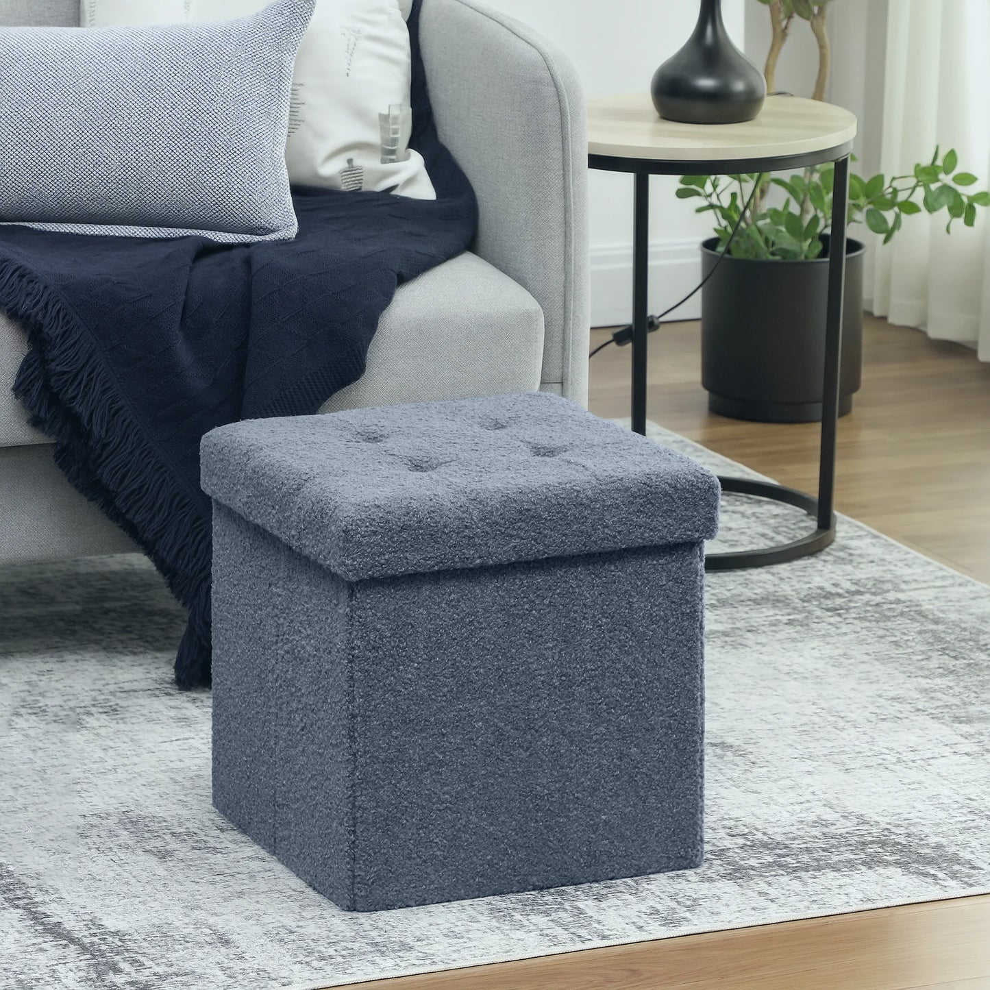 Blue ottoman in a living room setting with a sofa and side table.