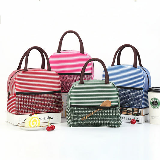 Four striped lunch bags in pink, red, green, and blue are arranged on a white background with decorative props including books, cherries, and a coffee cup.