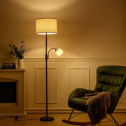 Living room with a green armchair, floor lamp, and fireplace.