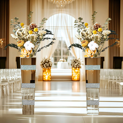 Decorative floral arrangements in tall vases with glittery bands on a formal event setting.