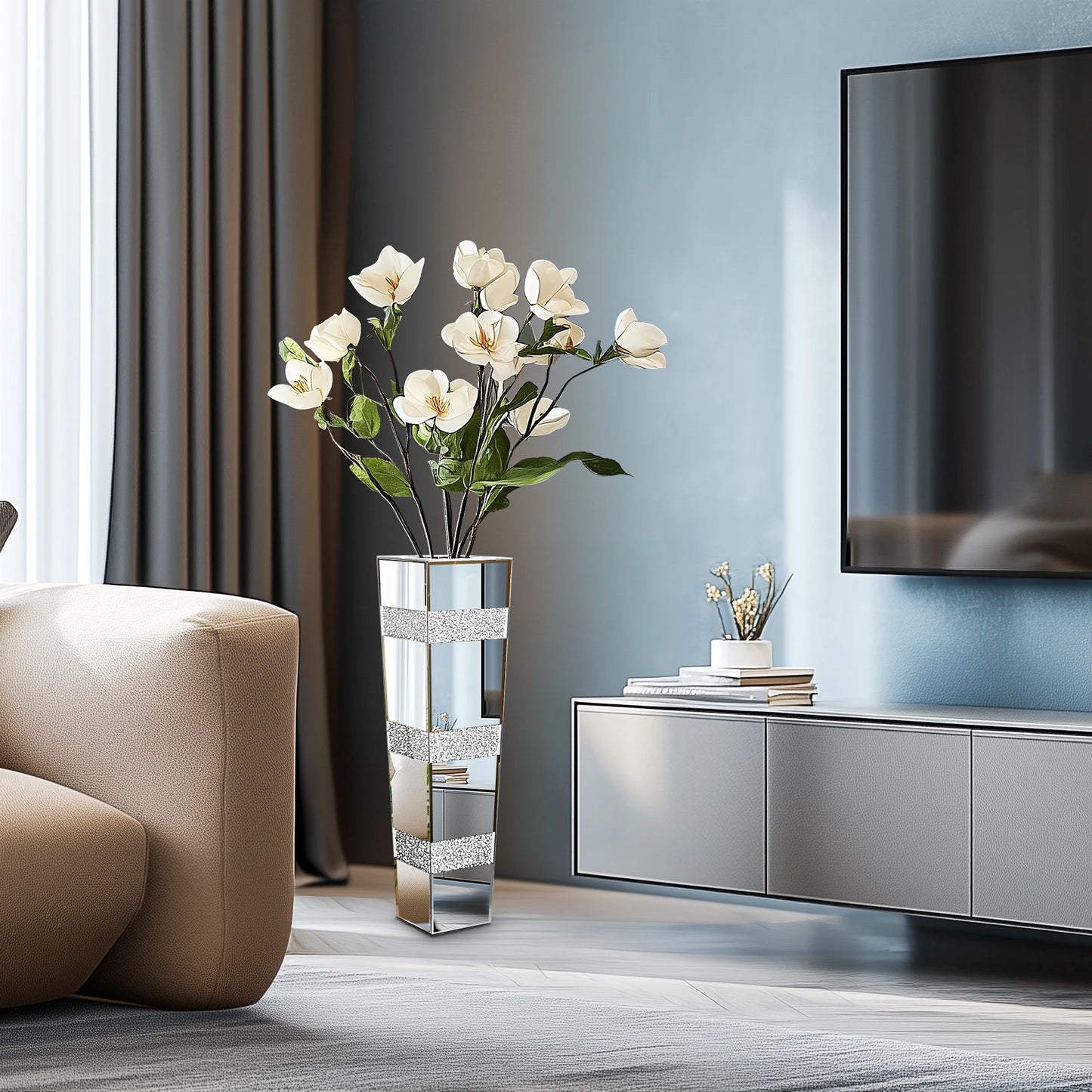 Modern living room with a vase of white flowers, a TV, and a beige armchair.