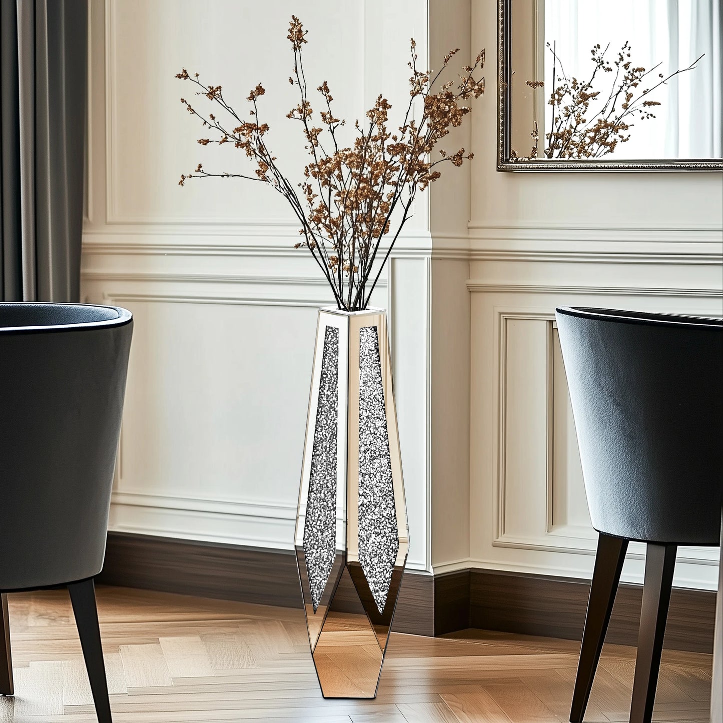 Tall decorative vase with dried branches in a room with two black chairs and a mirror.