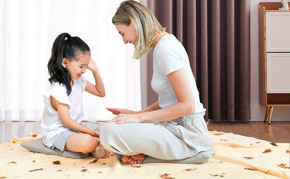 Woman and young girl sitting on the floor in a room with curtains and furniture.