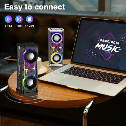 Two colorful speakers on a table next to a laptop with 'Music' displayed on the screen.