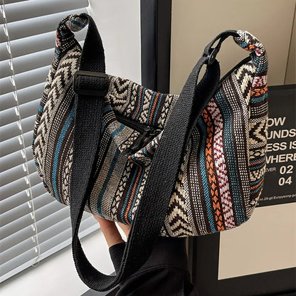 Patterned handbag with a black strap in front of a window with blinds.