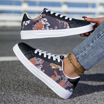 Black floral sneakers with white soles worn by a person on a road.