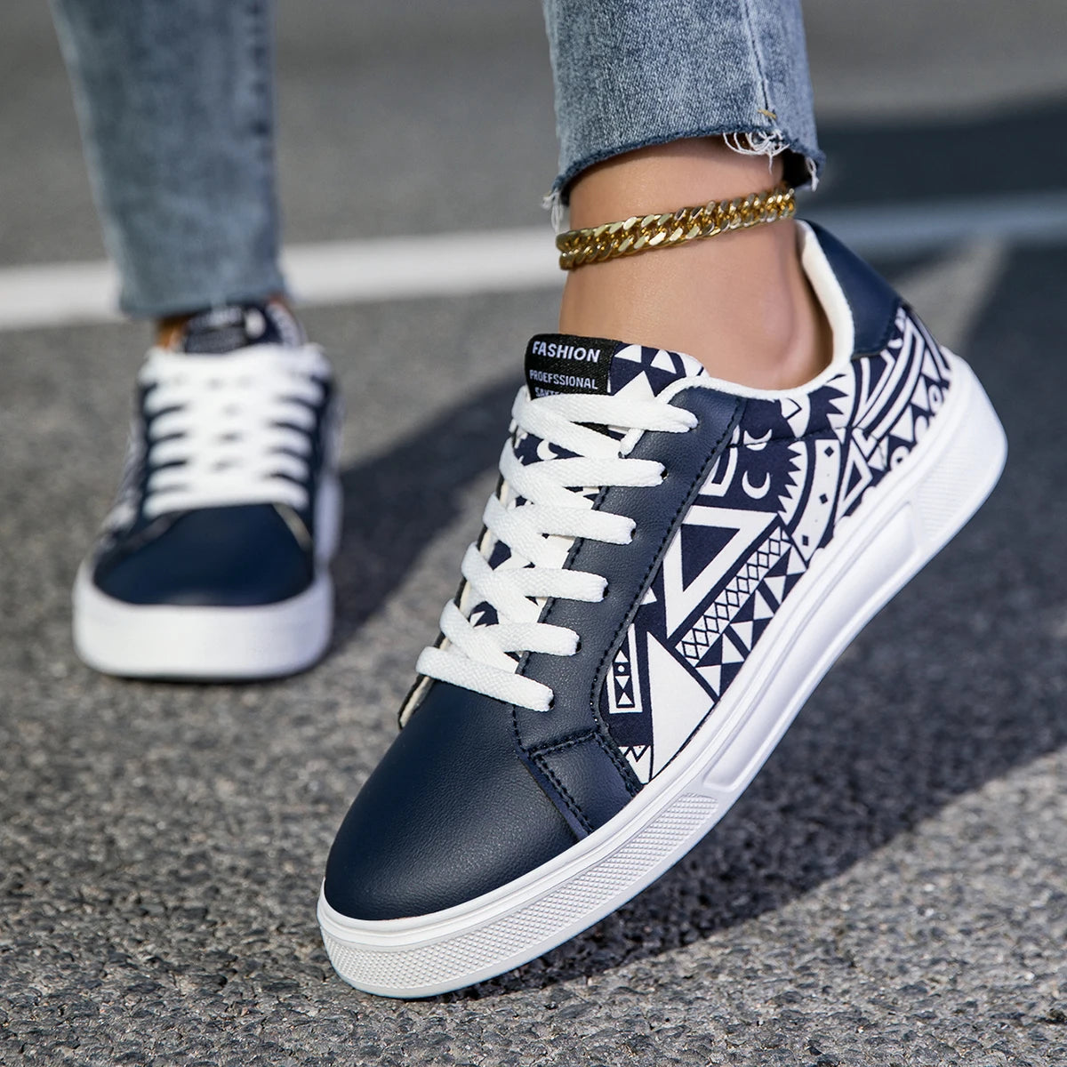 Navy blue sneakers with white patterns worn on a pavement.