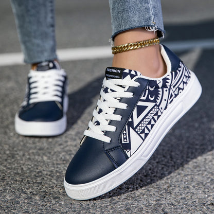 Navy blue sneakers with white patterns worn on a pavement.