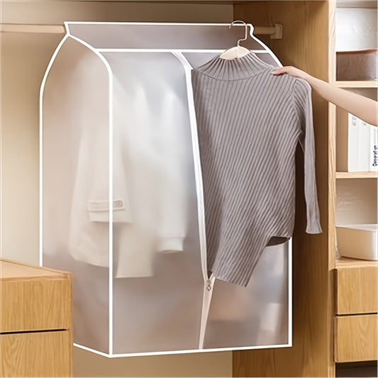 Clear garment cover with a sweater inside, held by a hand in a wooden wardrobe.