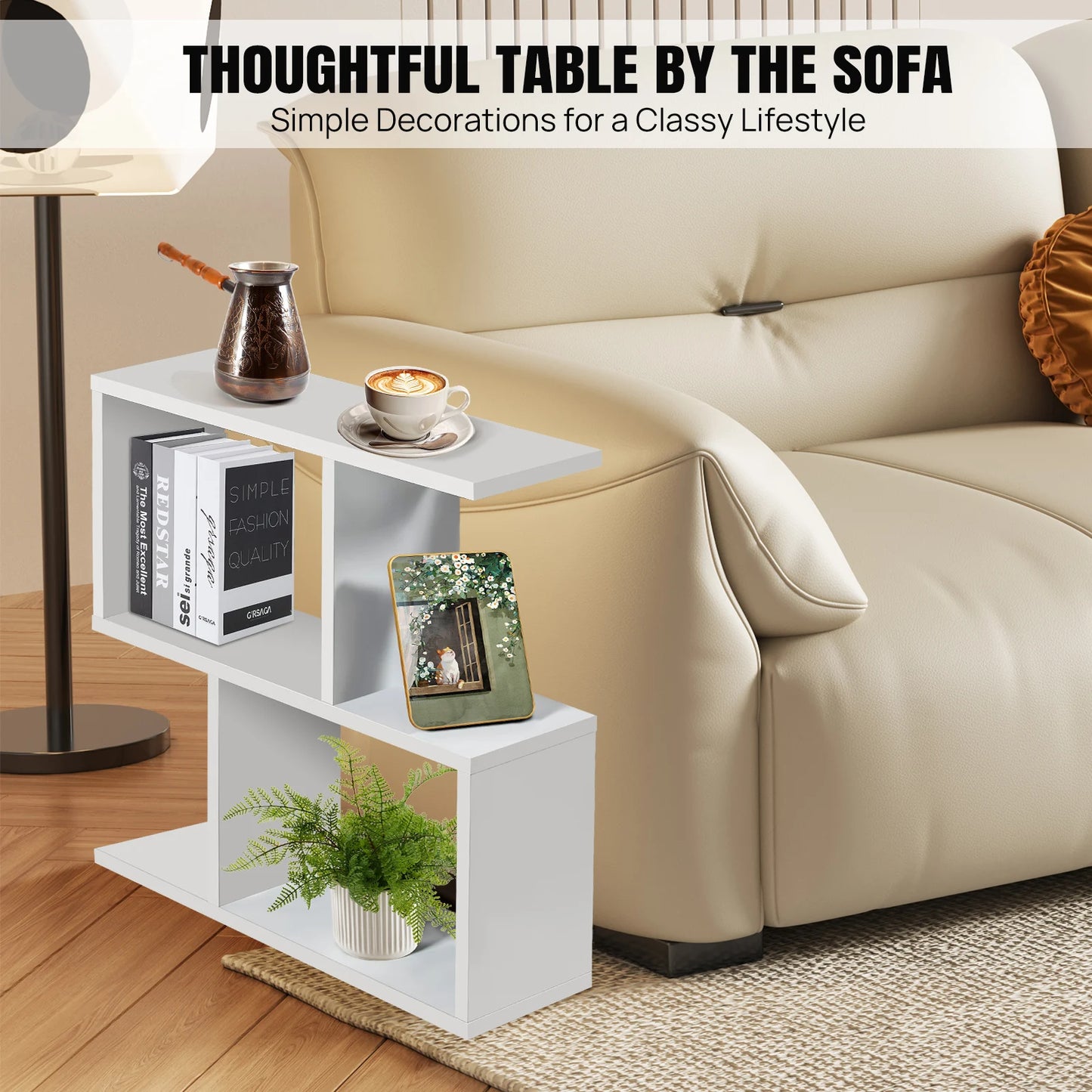 White side table with books, a plant, and a cup next to a beige sofa.