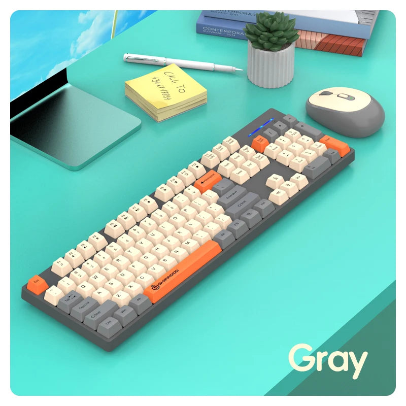 Gray mechanical keyboard on a desk with a tablet, mouse, and plant