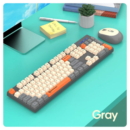 Gray mechanical keyboard on a desk with a tablet, mouse, and plant