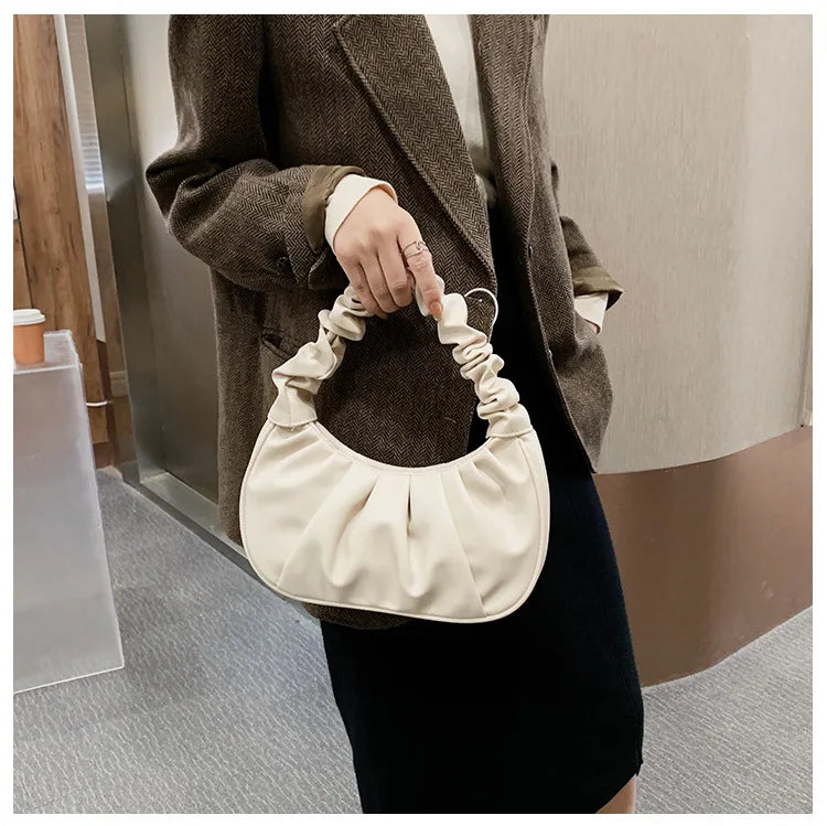 Person holding a beige handbag with a plain background