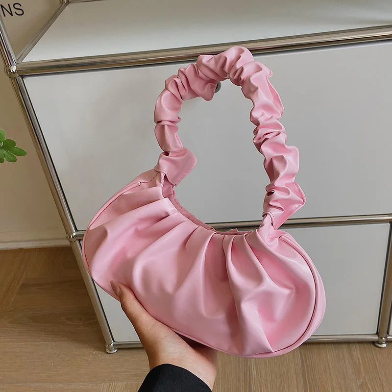 Pink satin handbag held in front of a glass cabinet.