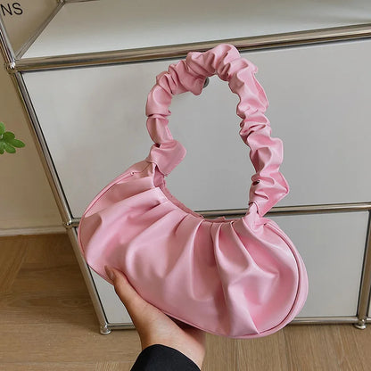 Pink satin handbag held in front of a glass cabinet.