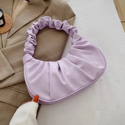 Purple fabric garment on a table with a beige coat and white surface.