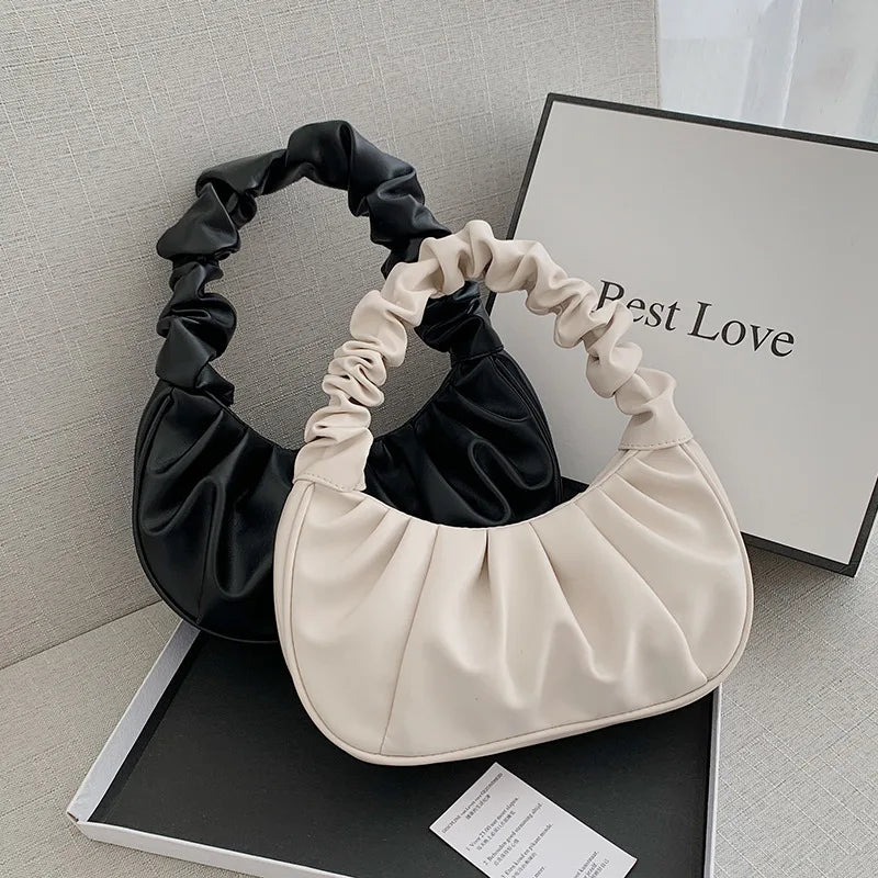 Black and beige handbag on a gray surface with a 'Best Love' box in the background.